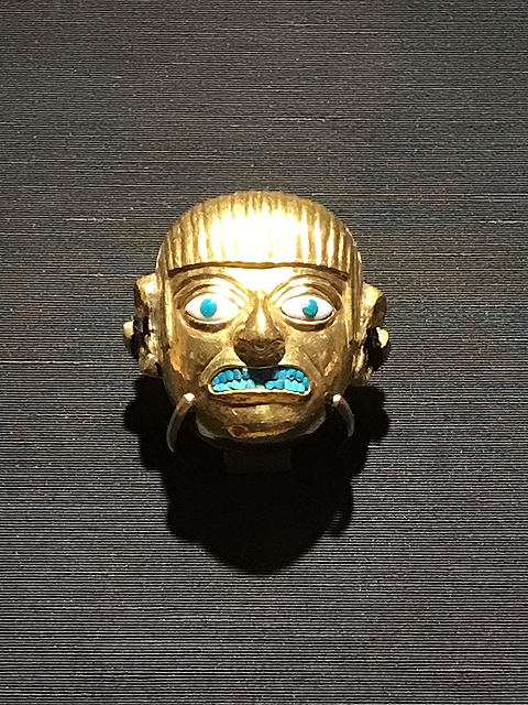 金地に象嵌（ぞうがん）された人面形の装飾品